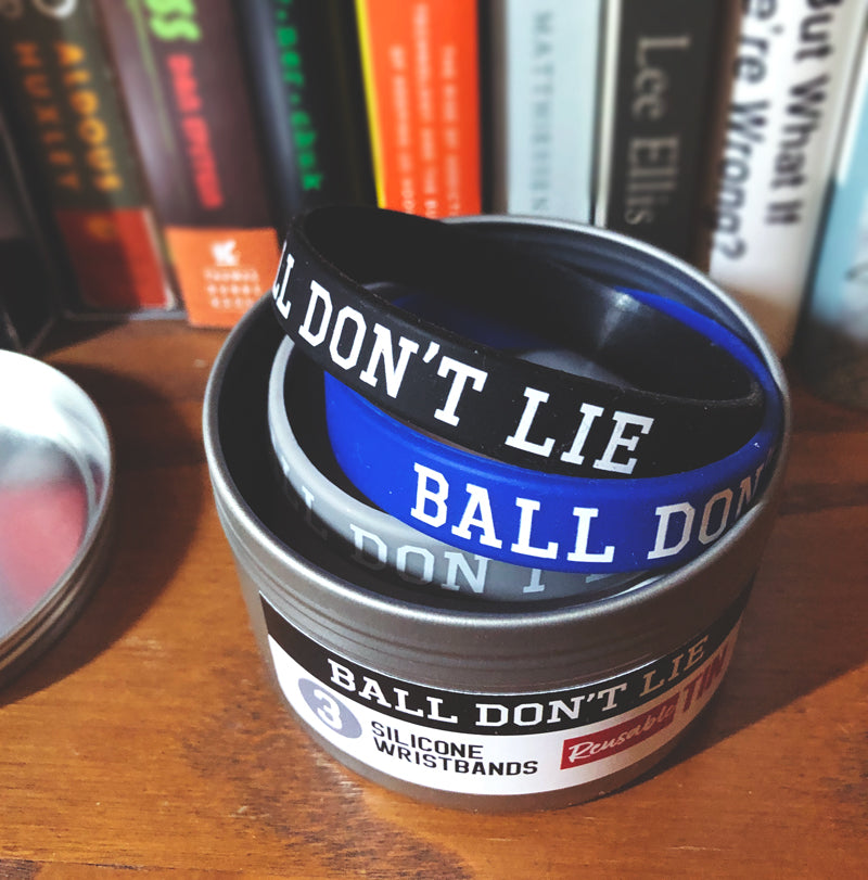 Open silver metal tin revealing three silicon wristbands with motivational slogan