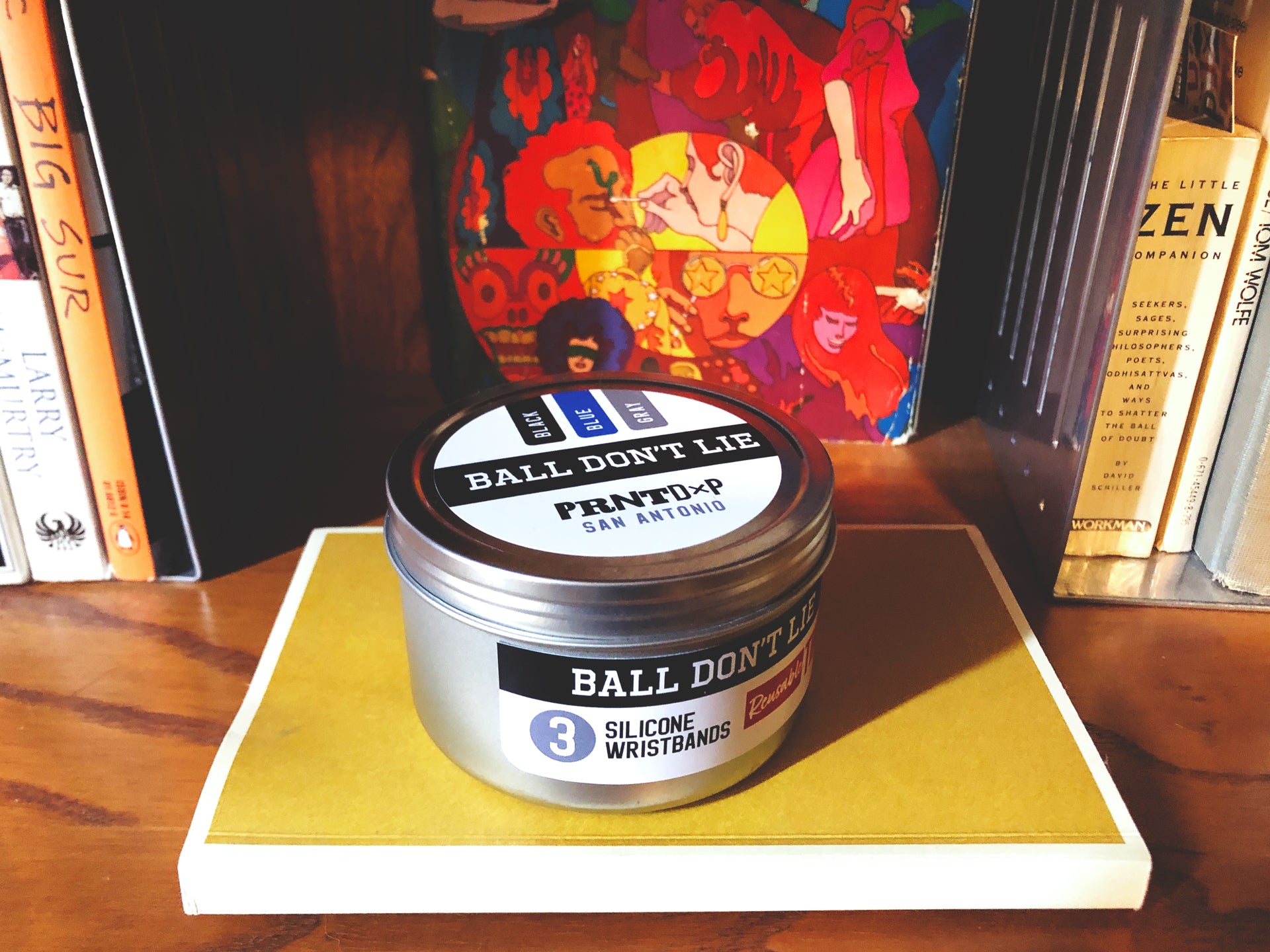 Small silver tin placed on top of yellow book on a bookshelf 