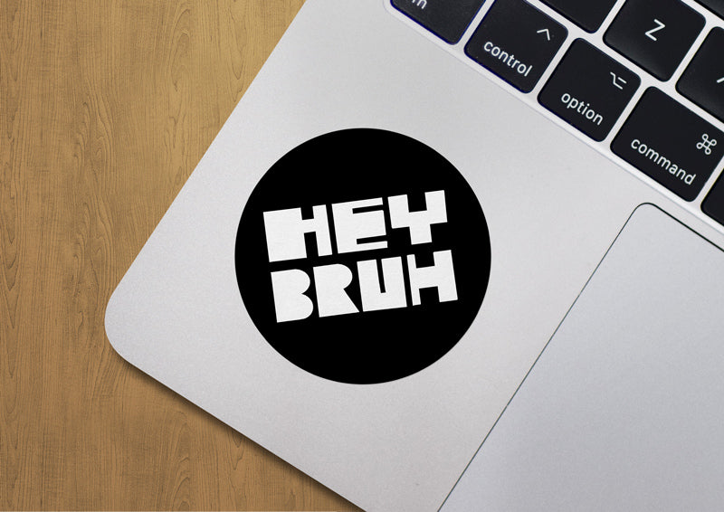Close up of a round sticker on an Apple Laptop that says, "Hey Bruh"