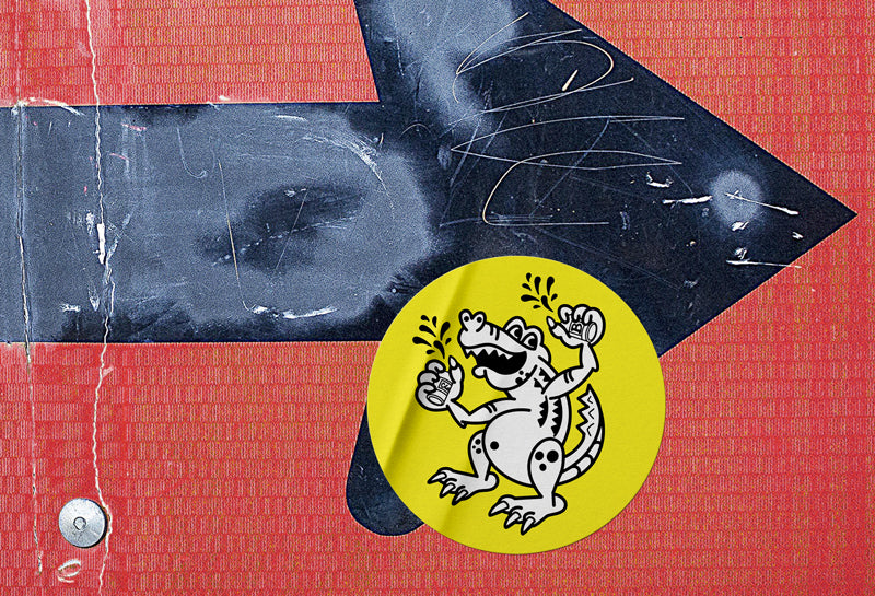 Close-up view of a round yellow sticker that has a funny illustration of an alligator with a big belly drinking beer