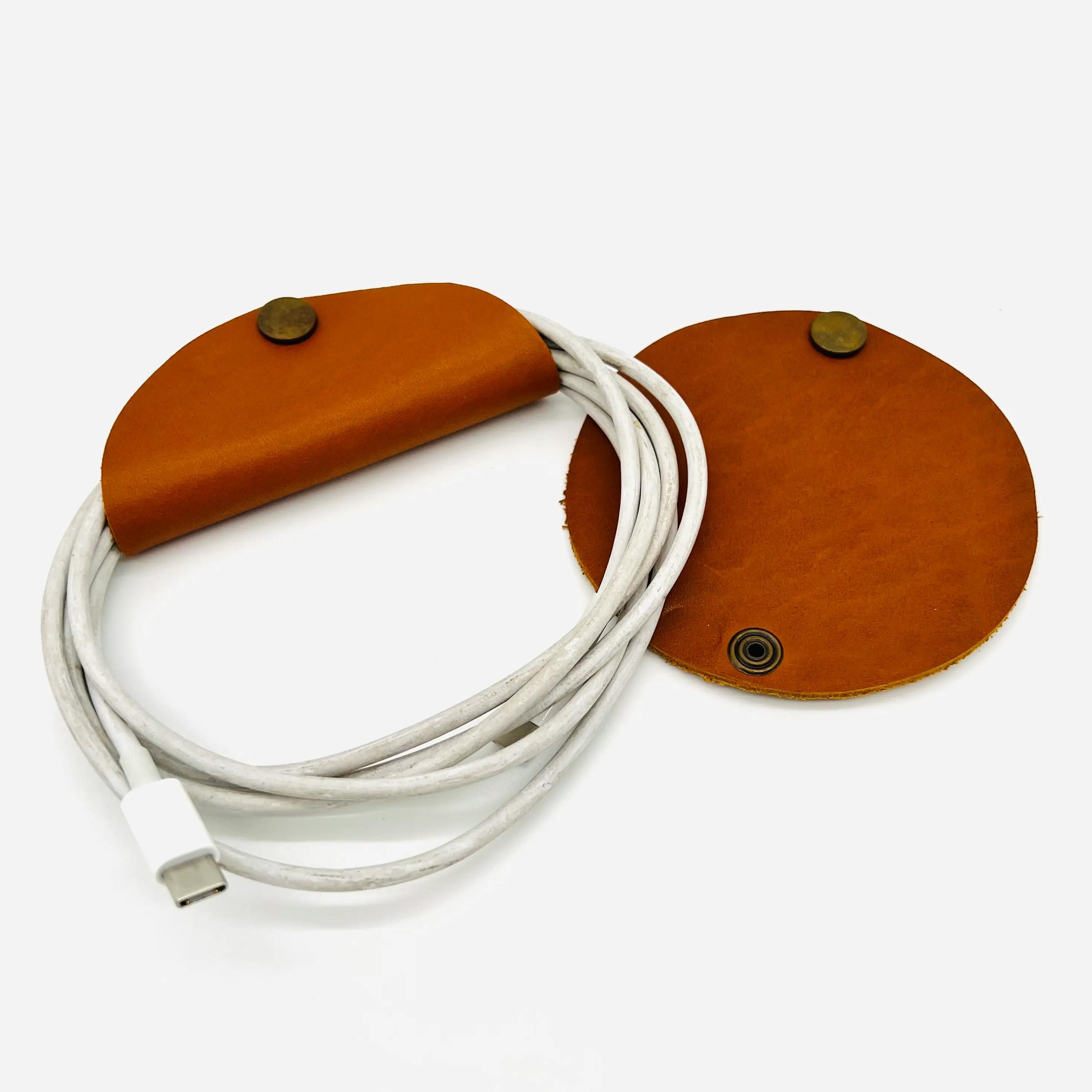 An open view of a leather cord organizer with a brass belt snap, commonly referred to as a 