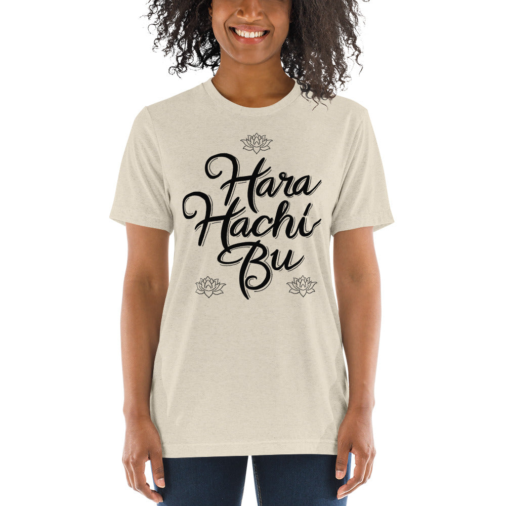 A young african american woman wearing an ash colored  t-shirt that says Hara Hachi Bu in a custom brush typeface.