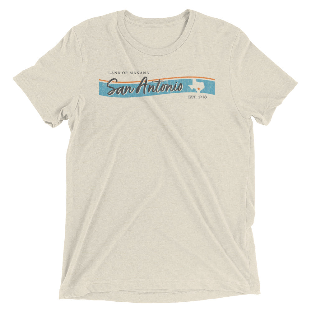 A wrinkled oatmeal color unisex t-shirt that has a distressed graphic printed on it that reads San Antonio, Texas