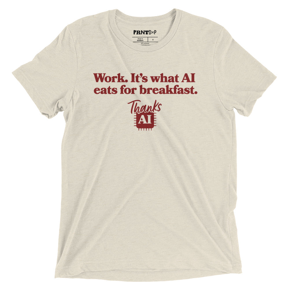 A photo of a flat t-shirt with a graphic printed on the front that says work, it's what AI eats for breakfast, Thanks AI.